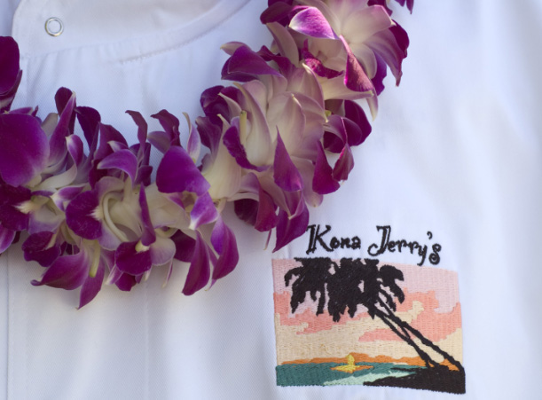 A purple lei and a white shirt with a palm tree on it.